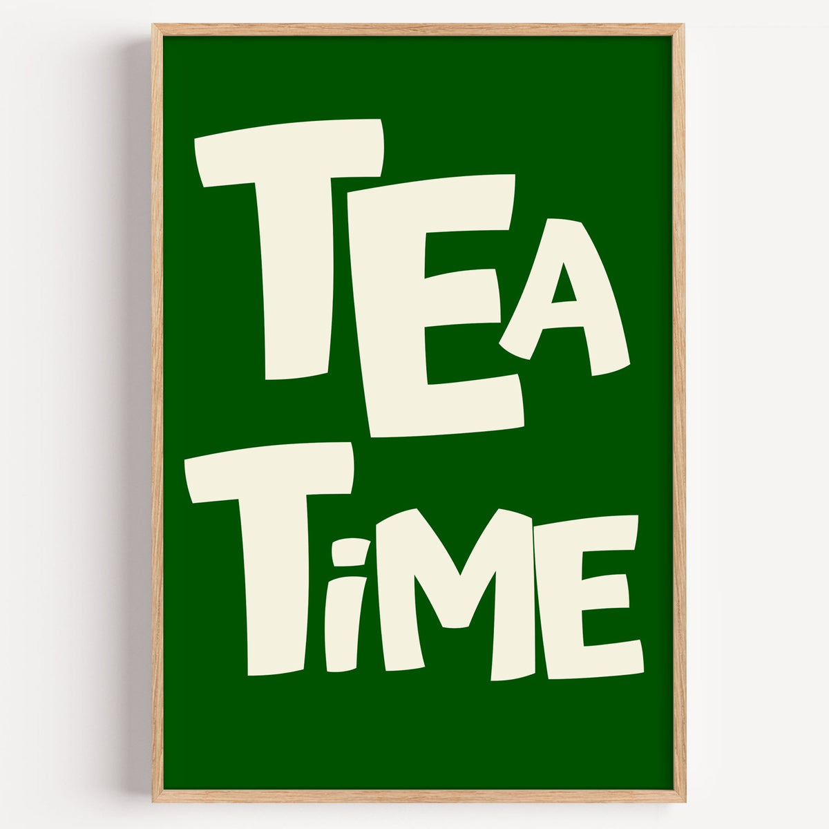 TEA TiME green typography print in a light oak frame on a plain white wall