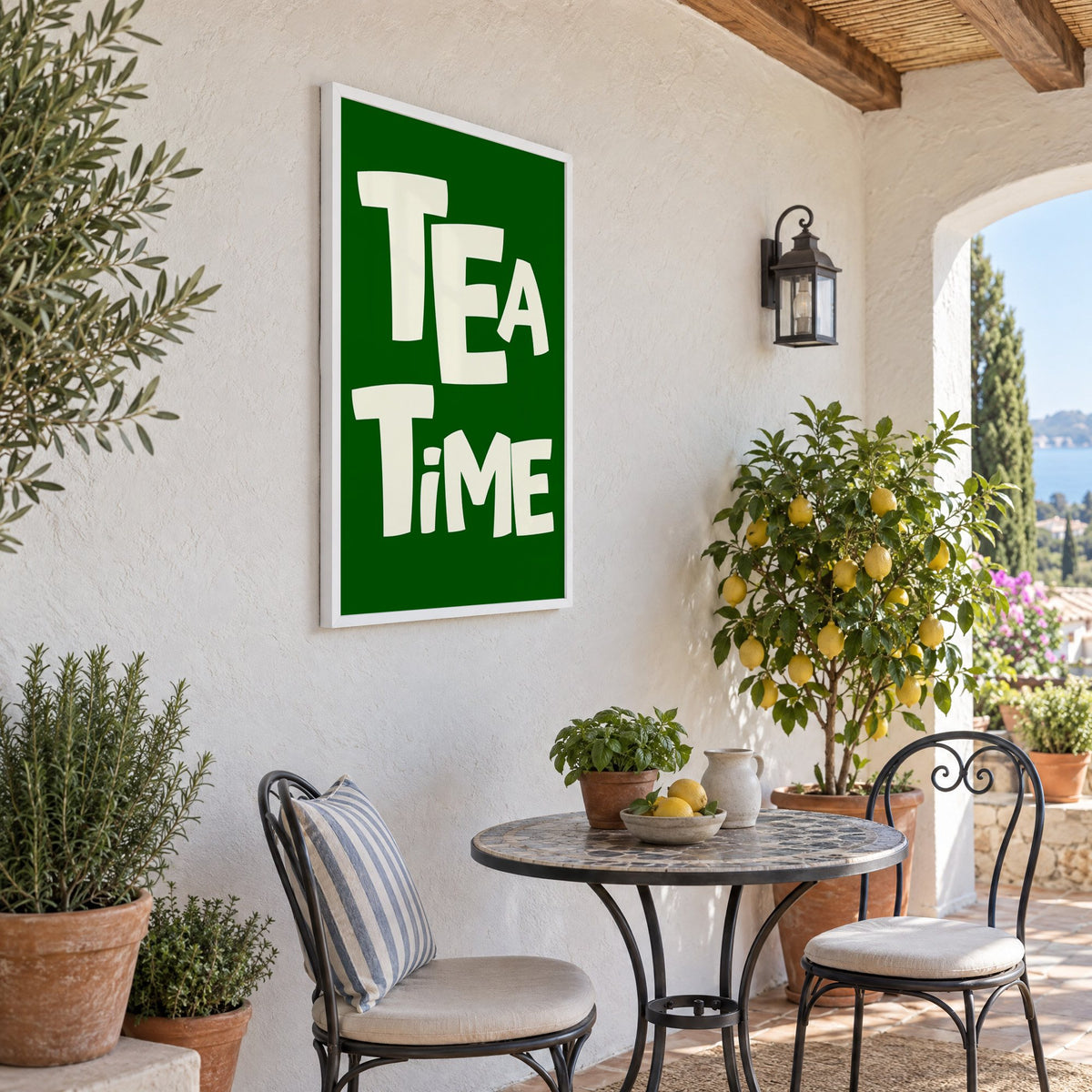TEA TiME green typography print in a white frame on a sunny patio wall beside a potted lemon tree