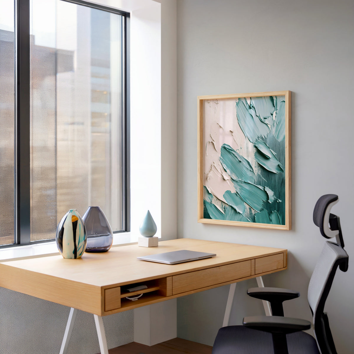 Teal and blush palette knife abstract print in a pale wood frame above a home office desk by a tall window