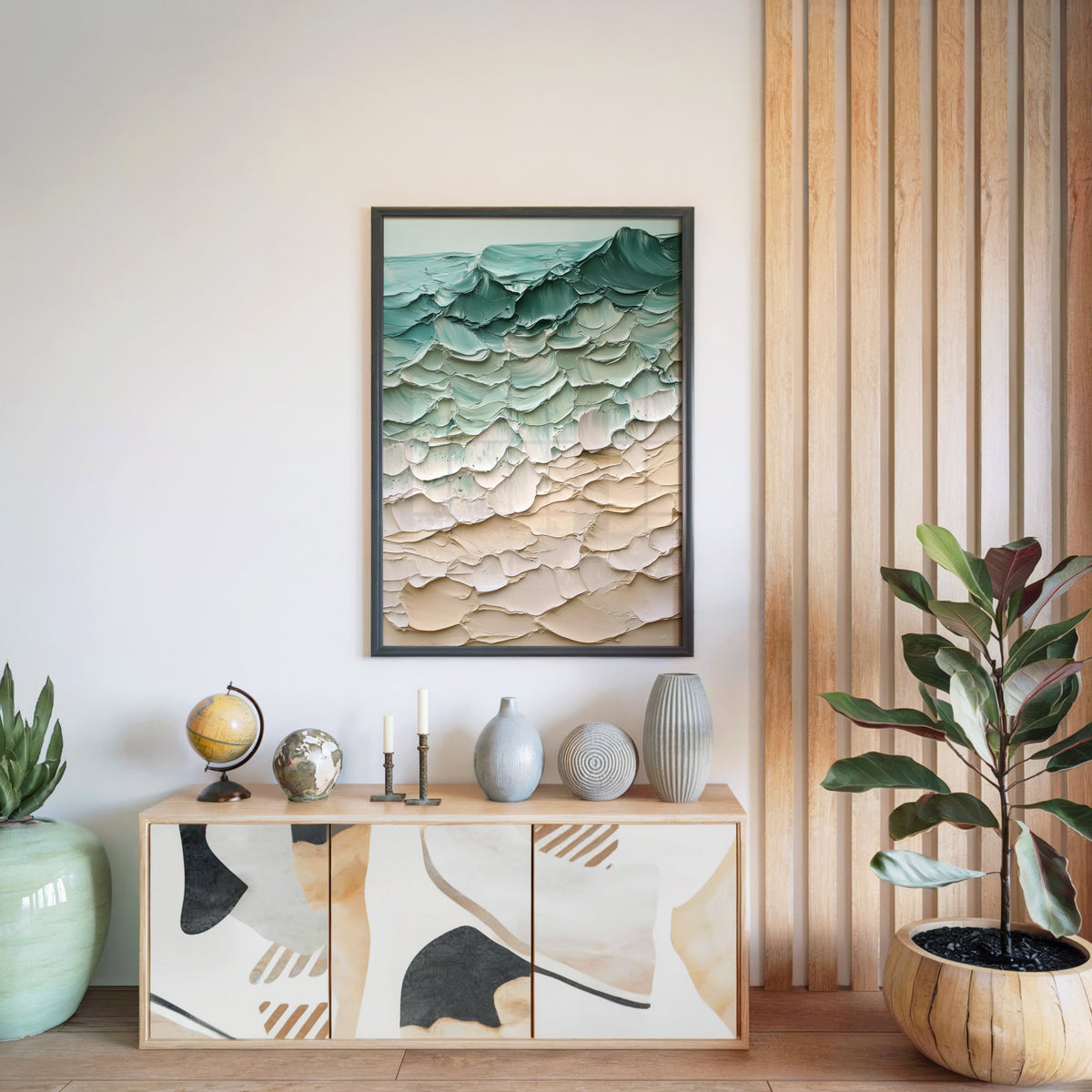 Teal and sand impasto shoreline abstract print in a black frame above a light wood sideboard by a wood slat wall