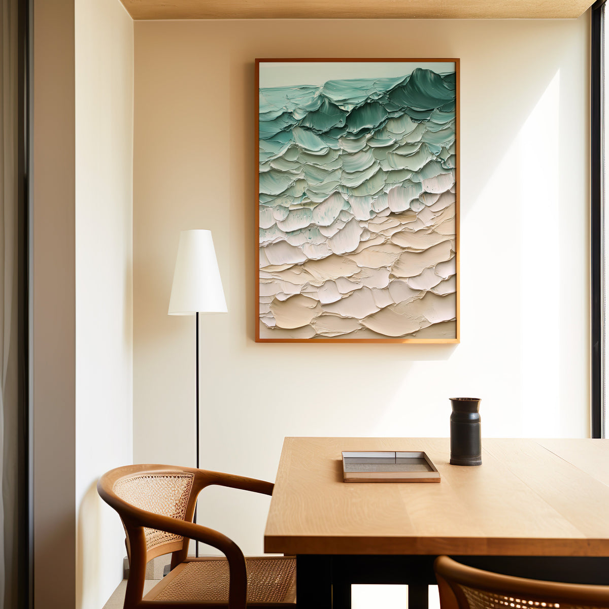 Teal and sand impasto shoreline abstract print in a slim oak frame above a dining table with a cane-back chair