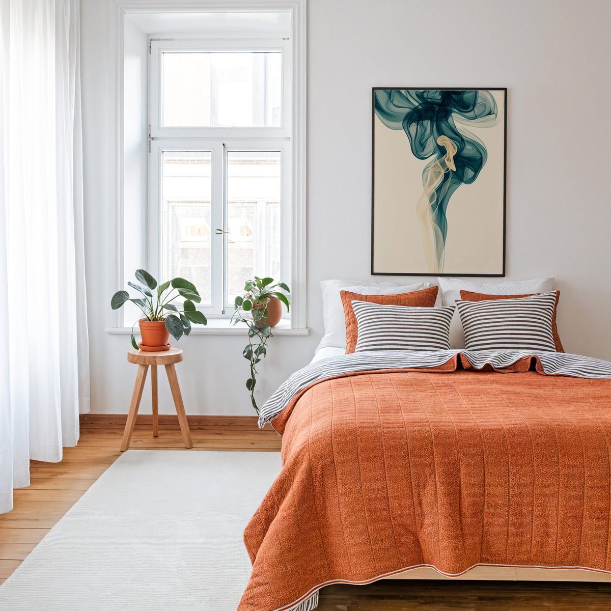 Teal smoke swirl fluid abstract print in a thin black frame above a bed with a rust orange quilt