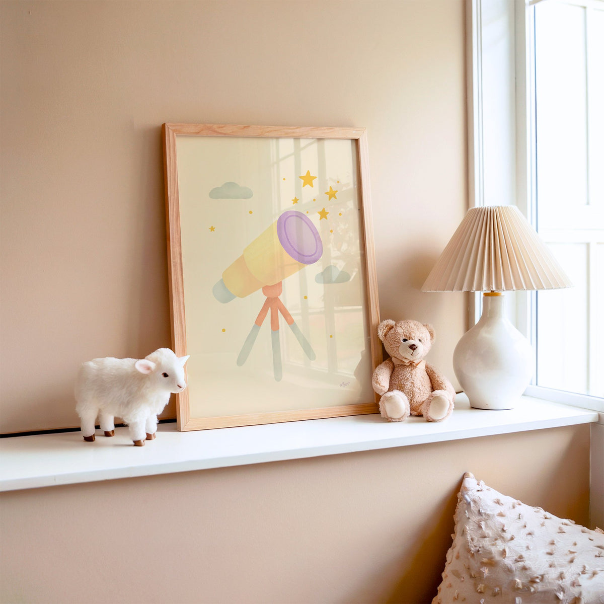 Pastel telescope and gold stars nursery print in an oak frame on a window ledge with a toy lamb and teddy