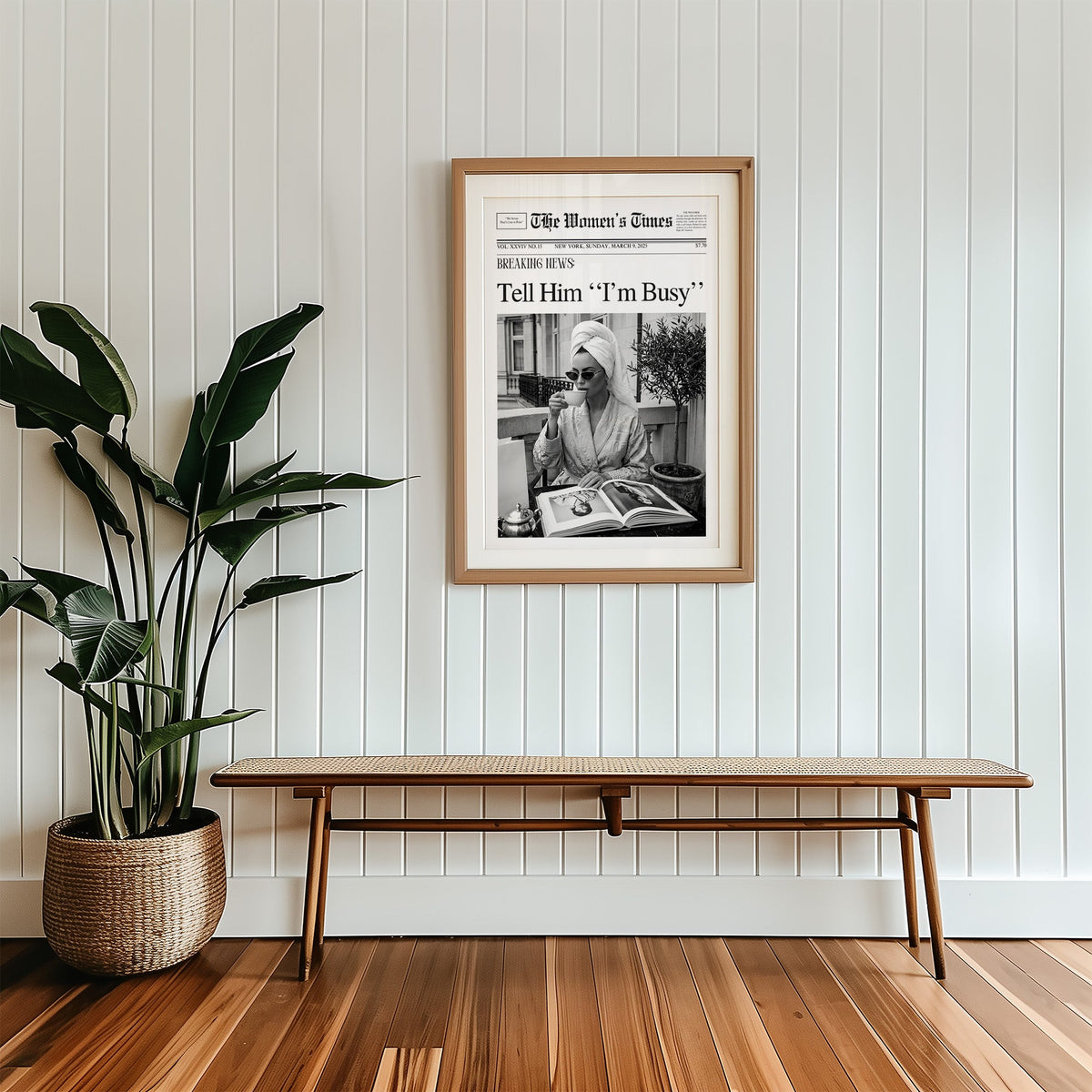 Woman with tea and photo book on balcony newspaper print in a wood frame with a white mat above a cane bench