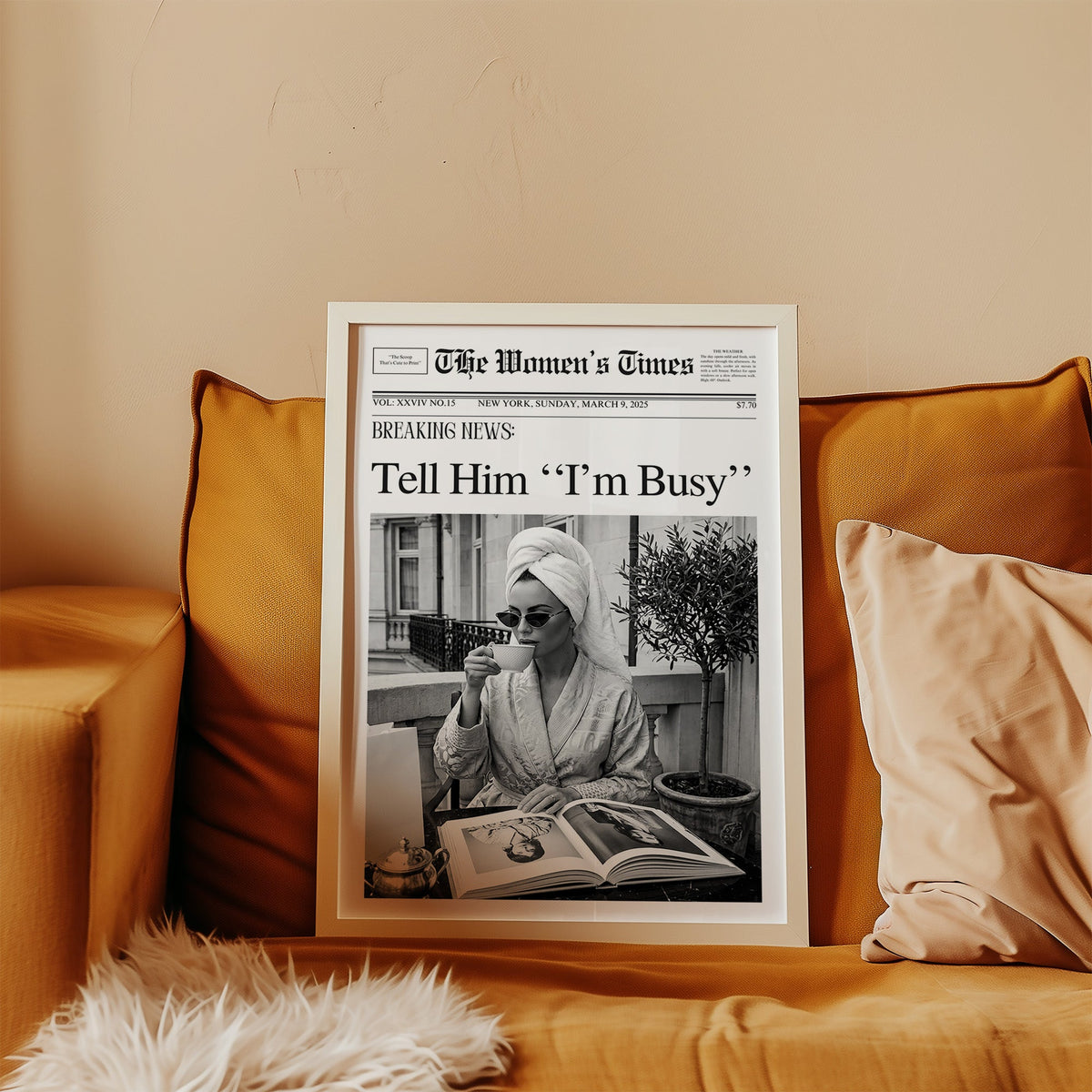 Woman with tea and photo book on balcony newspaper print in a white frame leaning on a mustard velvet sofa