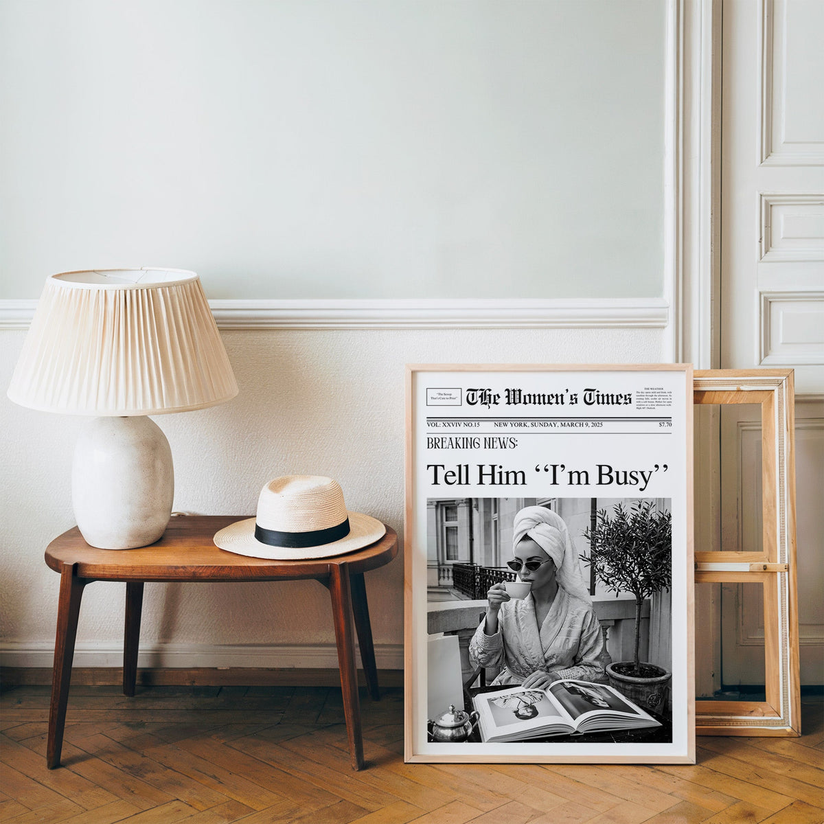 Woman with tea and photo book on balcony newspaper print in a pine frame on a wood floor beside a lamp and straw hat