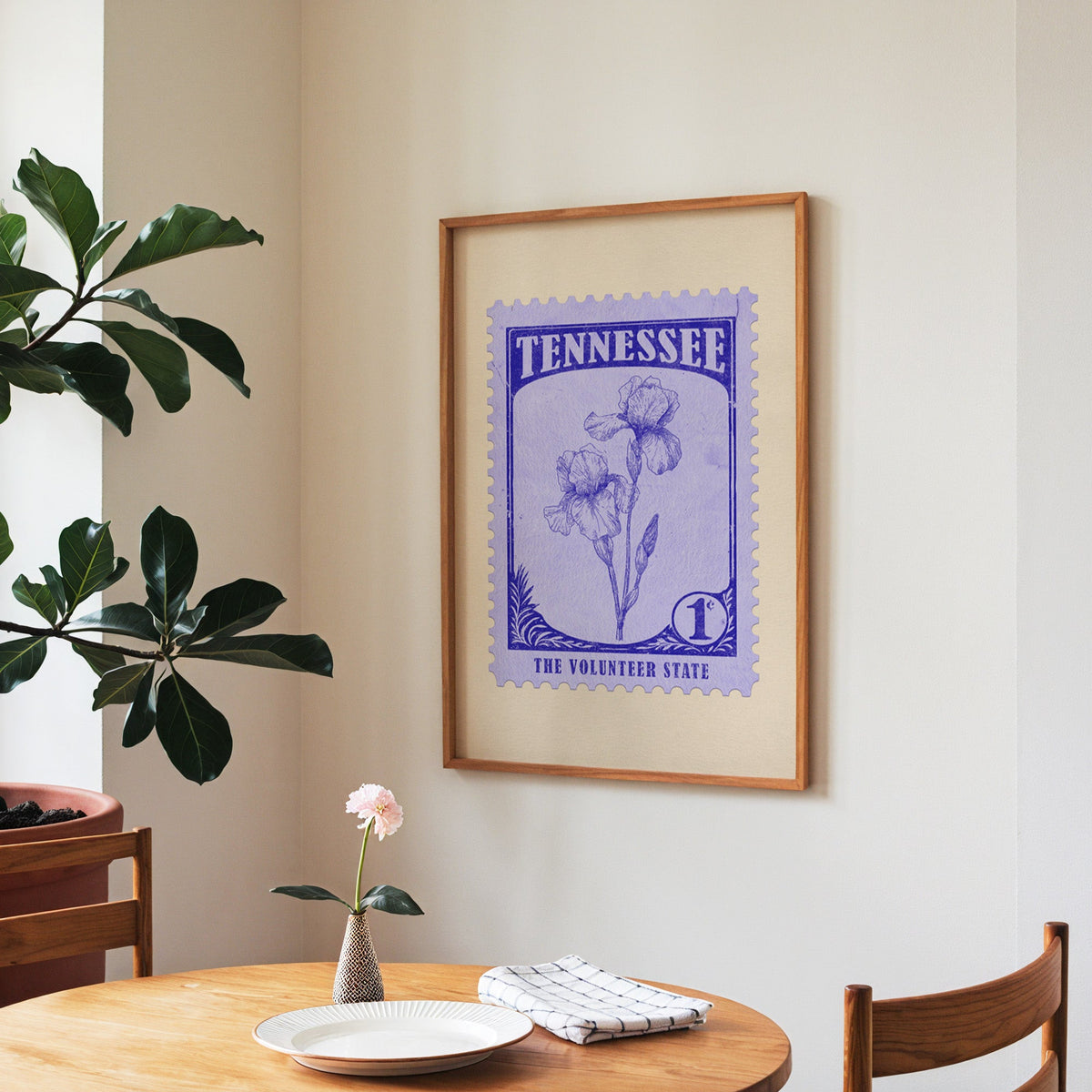 Tennessee state flower print framed above a round wooden table with a single bloom in a vase and books