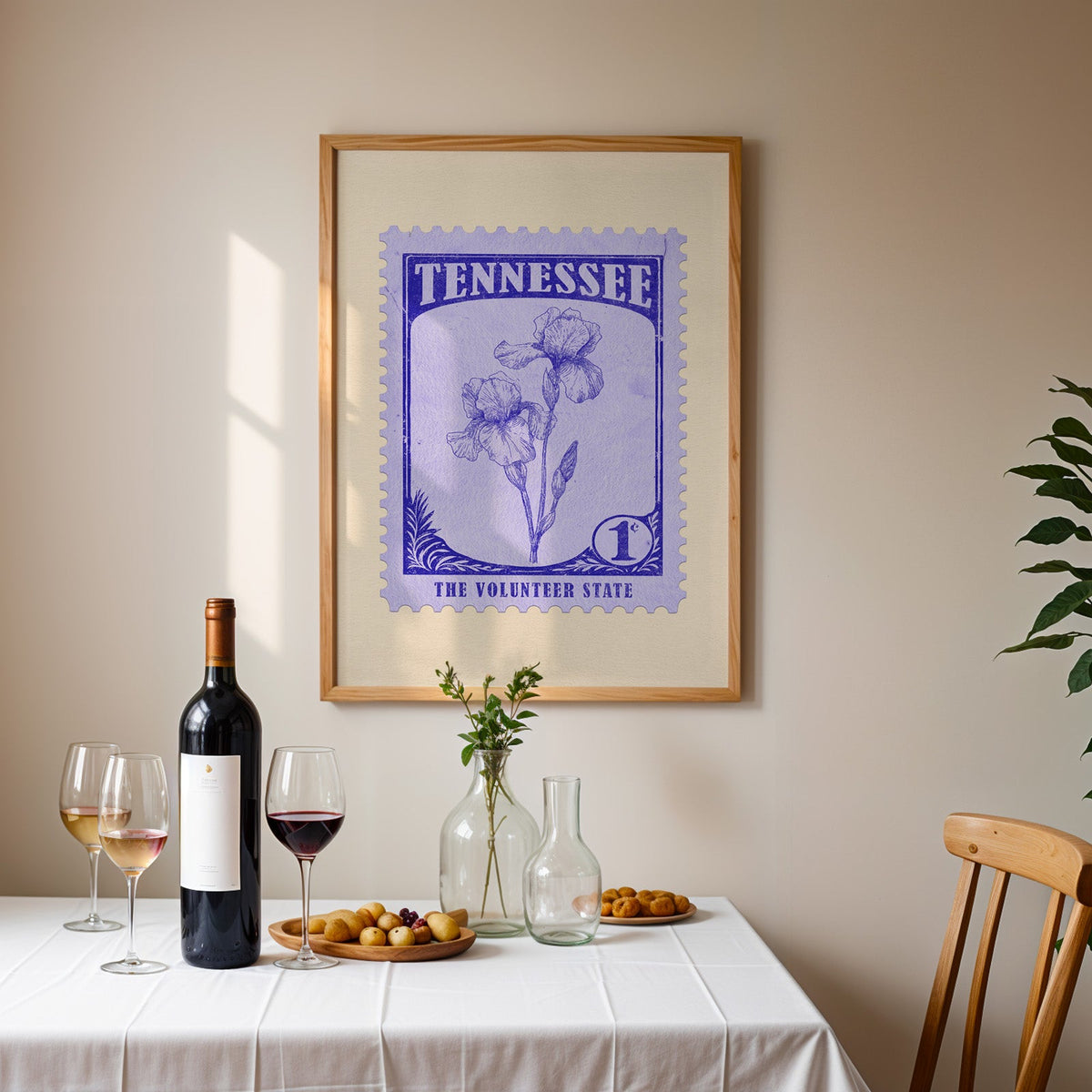 Tennessee stamp print framed on the wall above a dining table set with wine, glasses and olives
