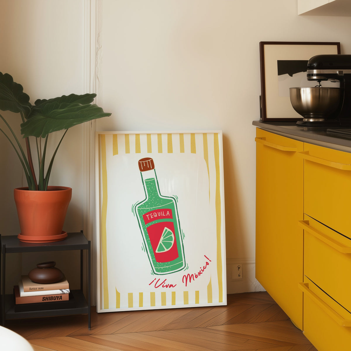 Tequila bottle print in a white frame on parquet beside a bright yellow kitchen