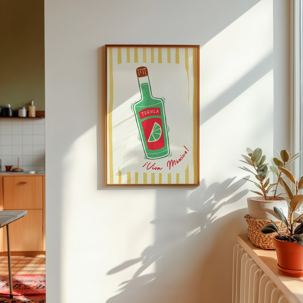 Tequila bottle print in a gold frame in sunlight with plants and a kitchen beyond