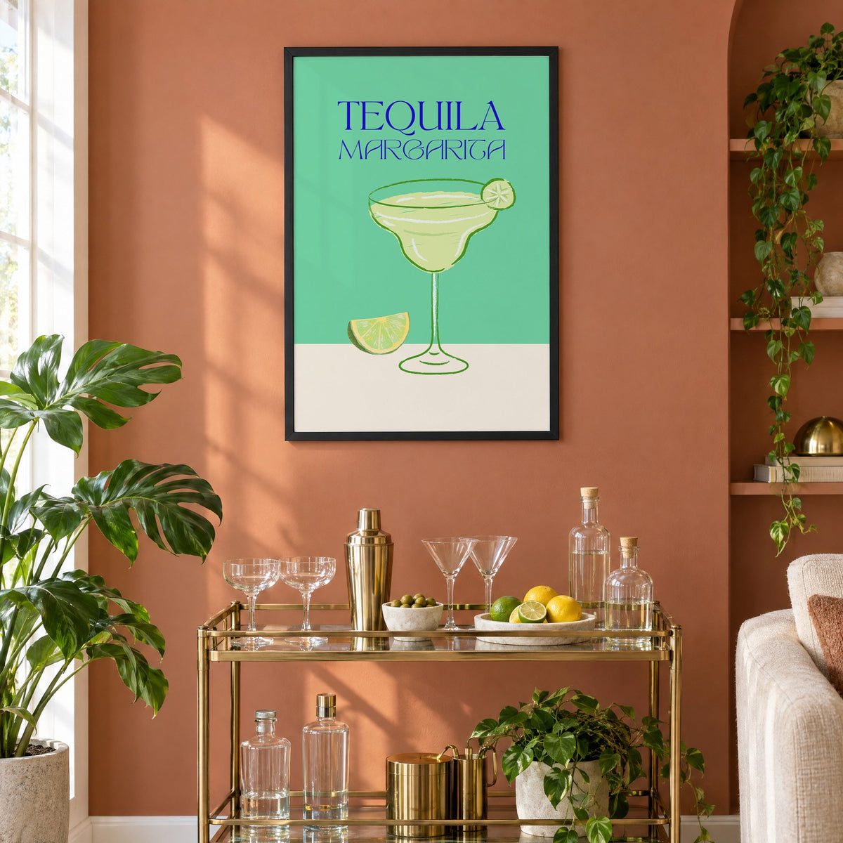 TEQUILA MARGARITA green glass and lime print in a black frame on a terracotta wall above a brass bar cart with coupes and citrus