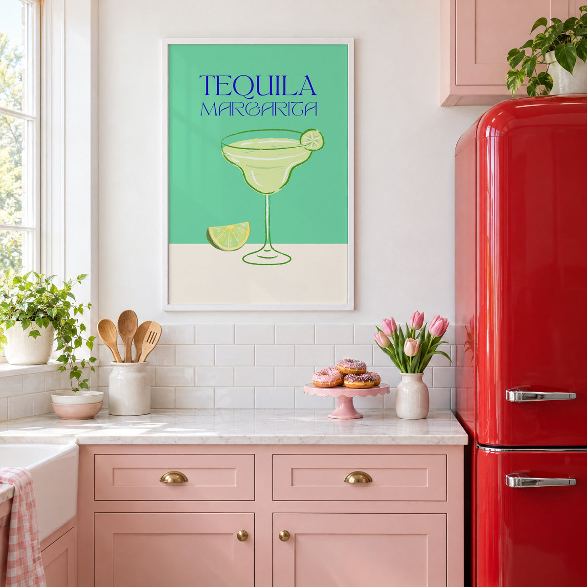 TEQUILA MARGARITA green glass and lime print in a white frame above pink cabinets beside a red retro fridge