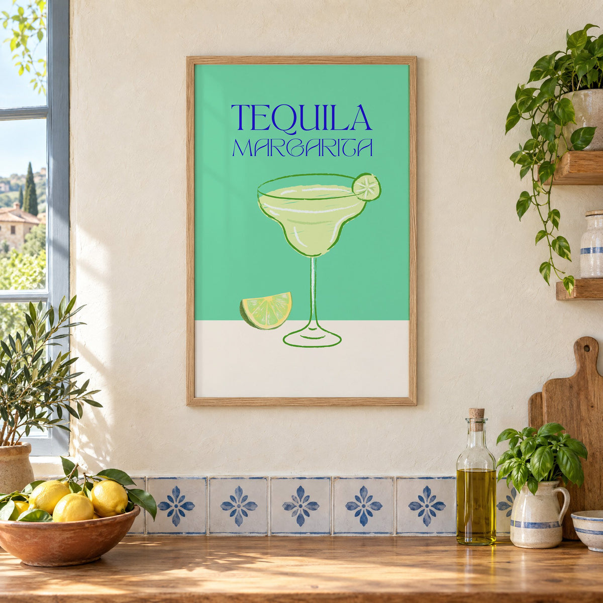 TEQUILA MARGARITA green glass and lime print in an oak frame on a cream plaster wall above a worktop with a bowl of lemons and blue-and-white tiles