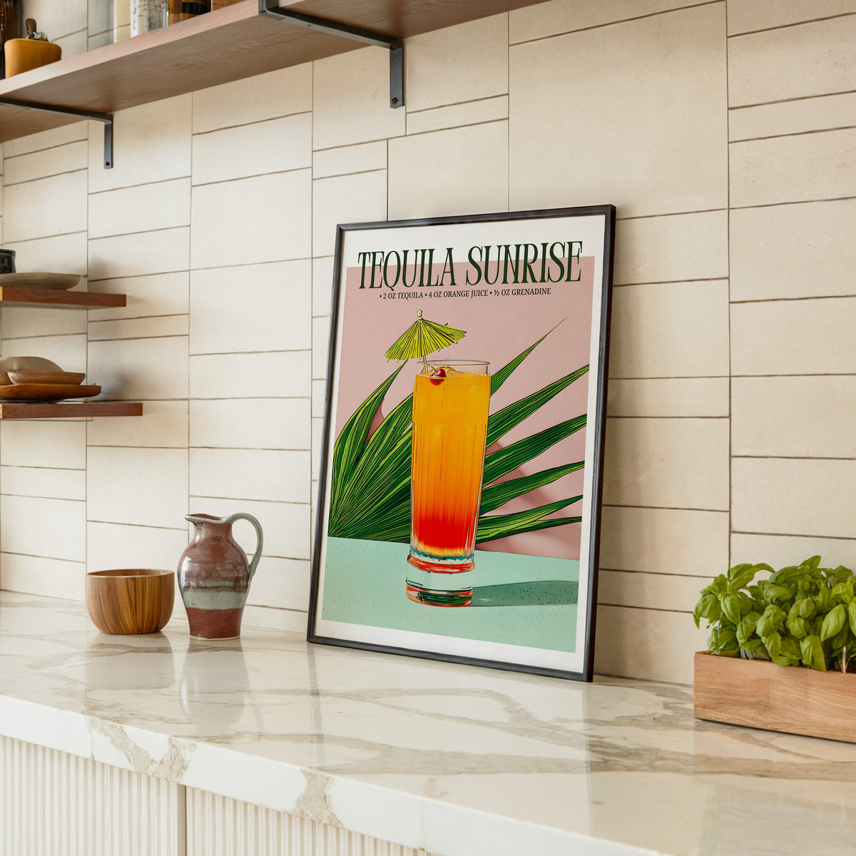 Tequila sunrise recipe print in a black frame leaning on a marble counter in a tiled kitchen