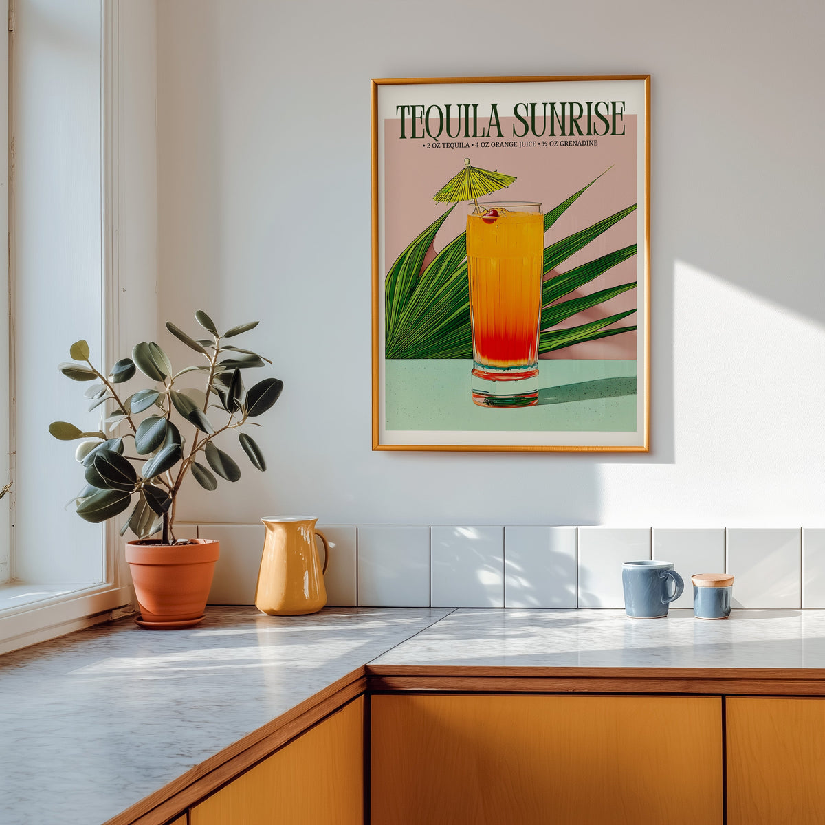 Tequila sunrise recipe print shown in a gold frame above a marble counter in a tan kitchen