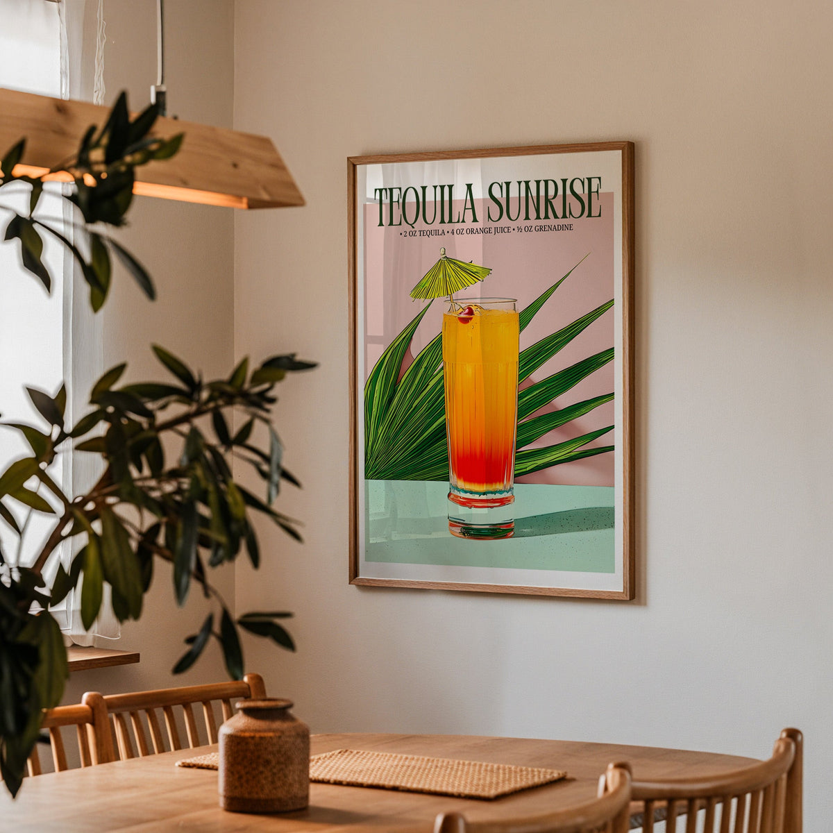 Tequila sunrise recipe print in a walnut frame above a dining table with olive branches