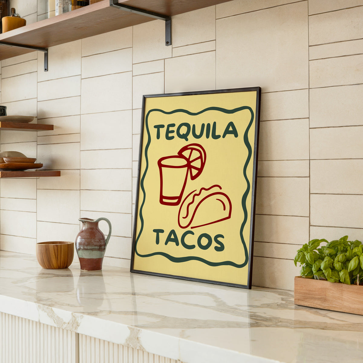 Tequila Tacos print in a black frame leaning on a marble counter in a tiled kitchen