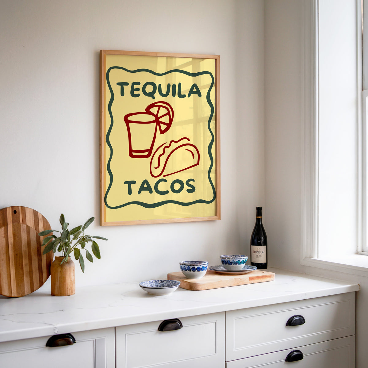 Tequila Tacos print in an oak frame above a white sideboard with a bottle of wine