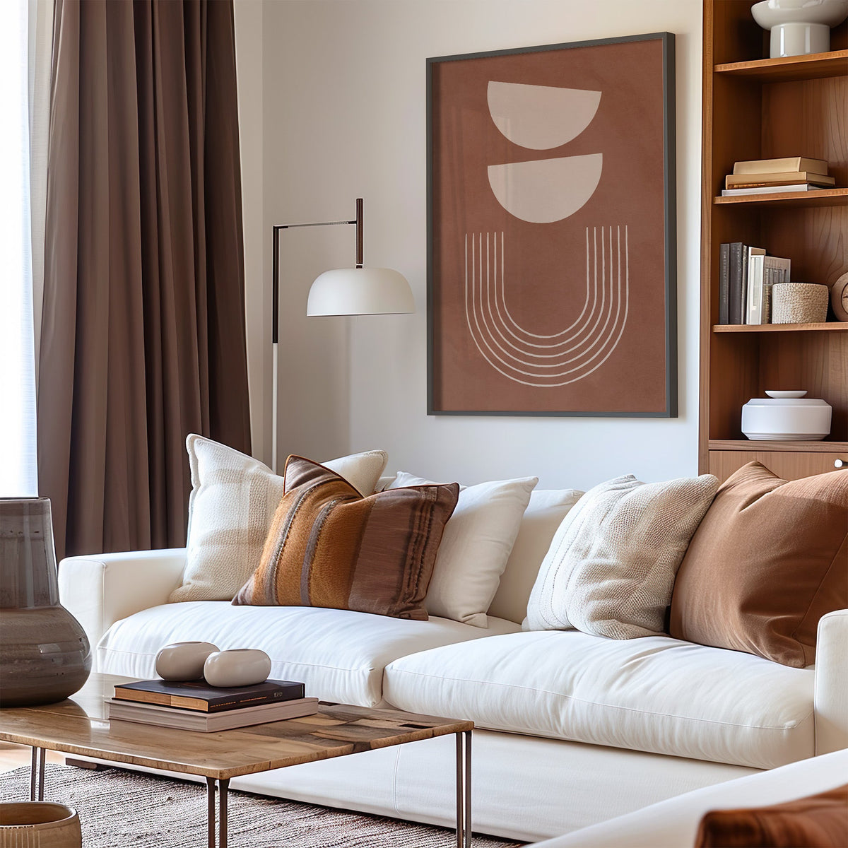 Cream bowls and line arch on terracotta print in a black frame above a cream sofa with brown striped pillows