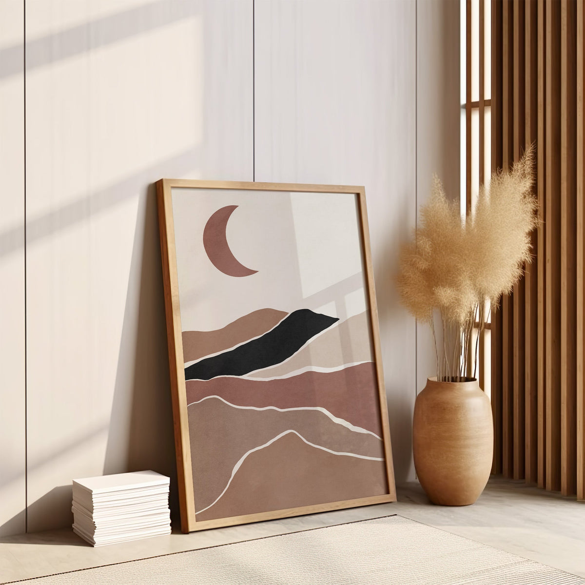 Terracotta crescent moon over hills boho print in an oak frame leaning on the floor by pampas grass and a wood slat screen