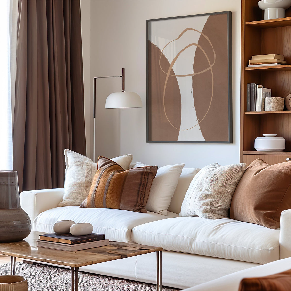 Terracotta twin arches and loops boho print in a black frame above a cream sofa with brown striped pillows