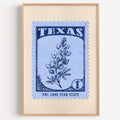 Texas state flower stamp print in navy on light blue, light oak frame on a plain white wall