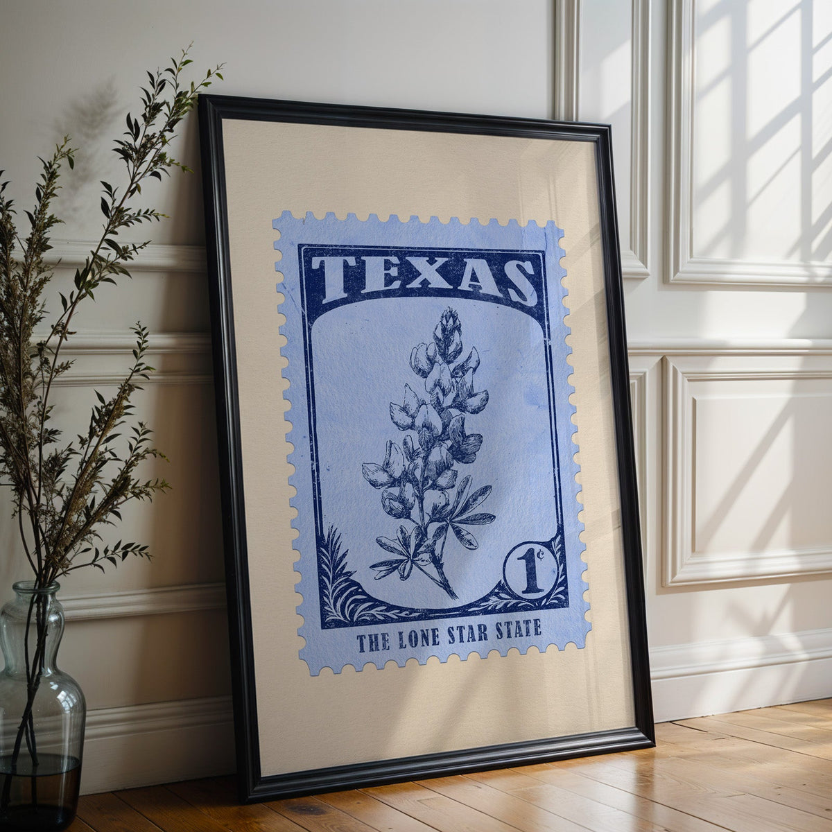Texas state flower print in a black frame leaning against a white panelled wall beside olive branches