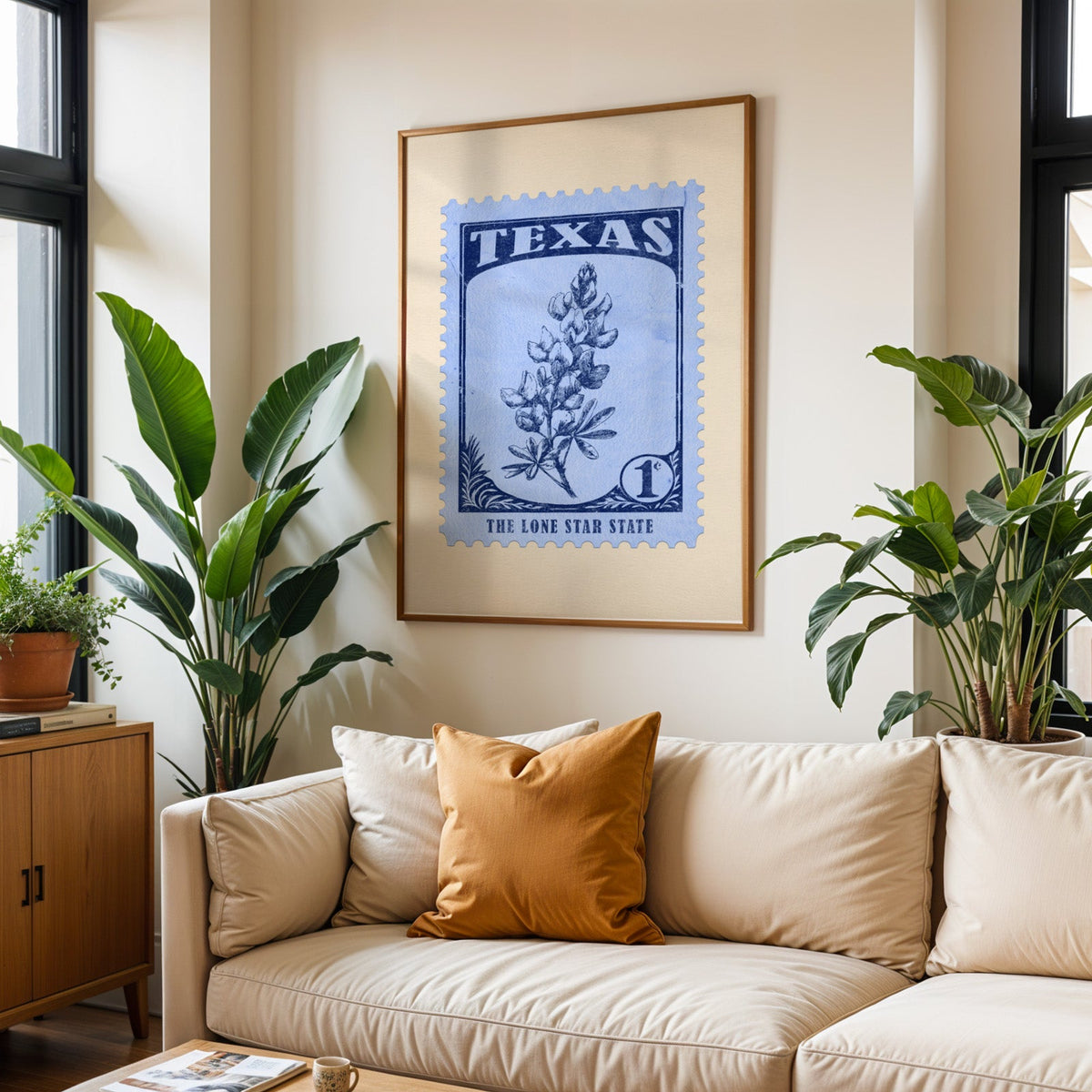 Texas state flower print framed above a cream sofa with an ochre cushion and large plants either side