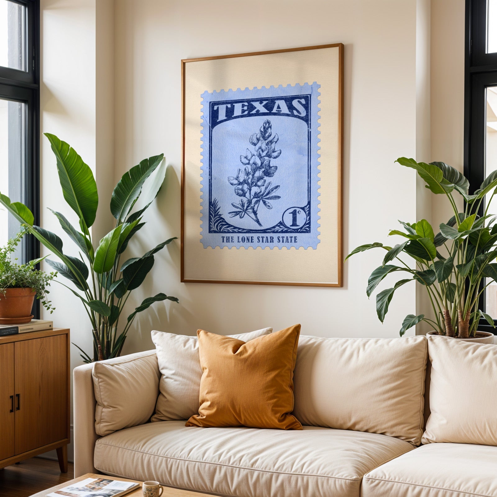 Texas state flower print framed above a cream sofa with an ochre cushion and large plants either side