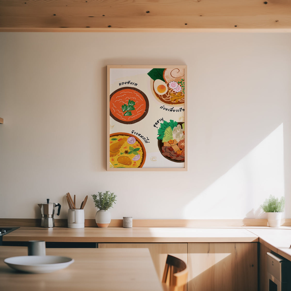 Thai food bowls print in an oak frame above a wood counter with a moka pot and herbs