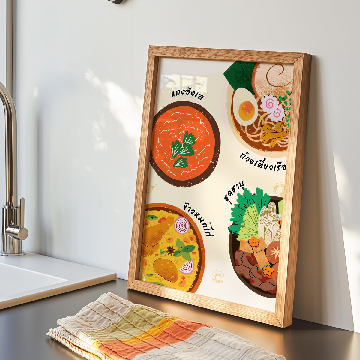 Thai food bowls print in an oak frame by the kitchen sink beside a striped tea towel