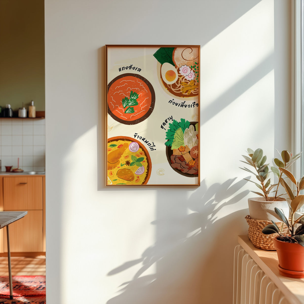 Thai food bowls print shown in a gold frame in sunlight with plants and a kitchen beyond