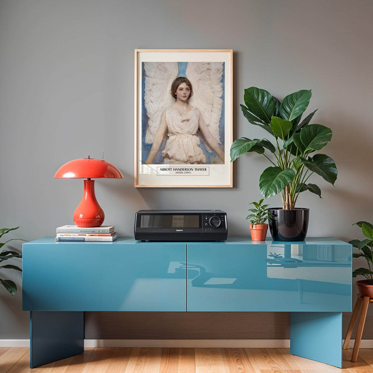 Angel poster in an oak frame above a teal sideboard with a red lamp
