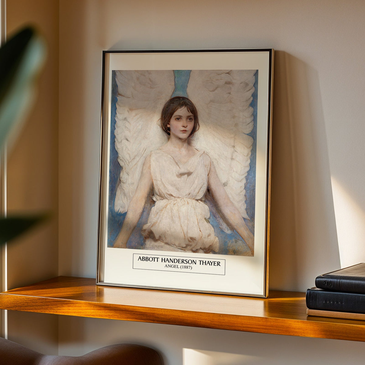 Angel painting print in a black frame on a walnut shelf in evening light