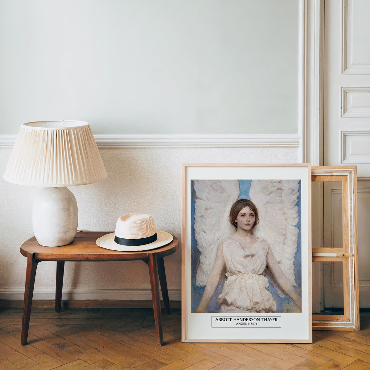 Thayer poster in a light wood frame leaning by a bench and panama hat