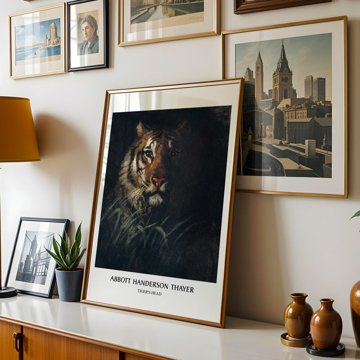 Tiger print shown in a gold frame leaning on a sideboard in a gallery wall