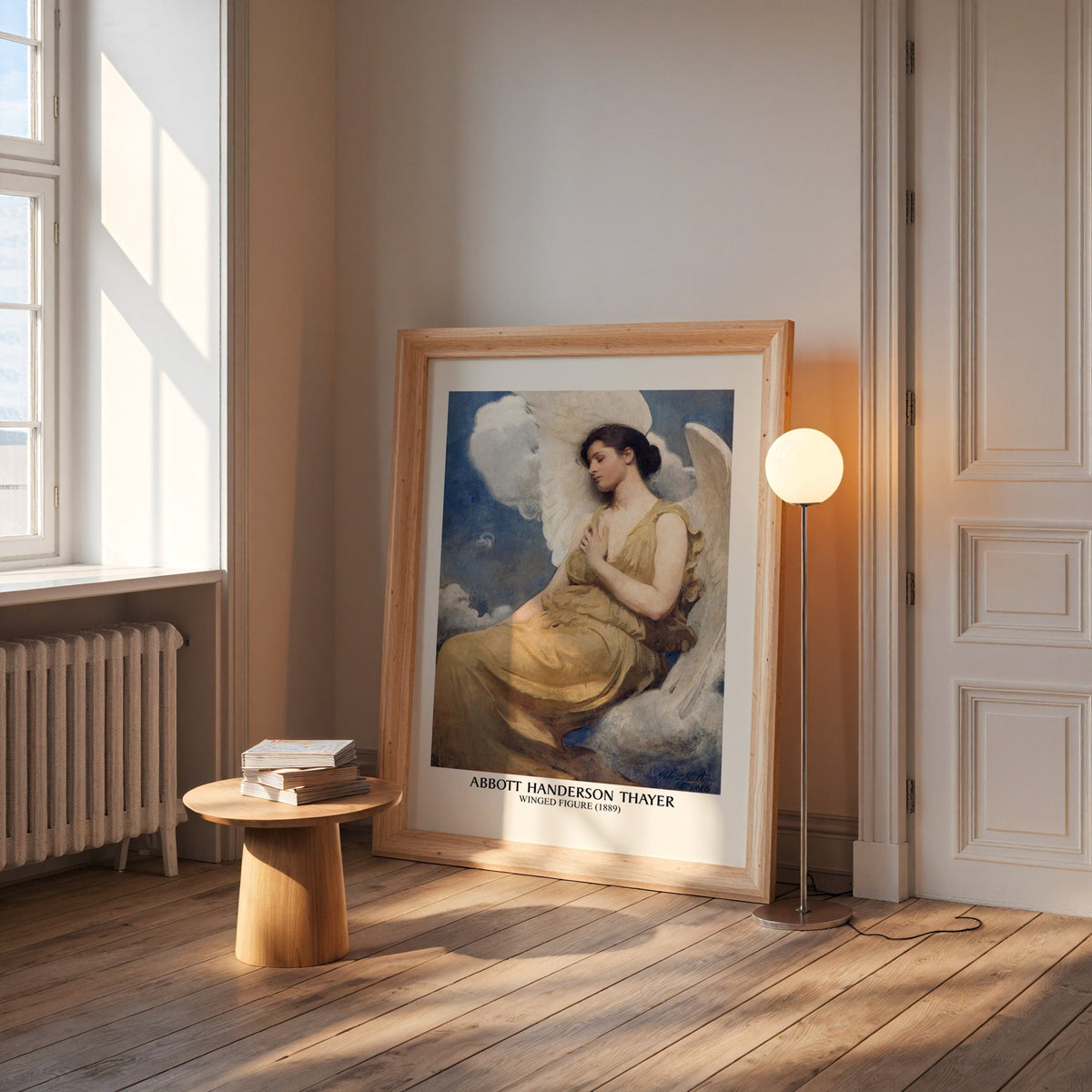 Winged figure print in a wide pine frame leaning by a sunlit window