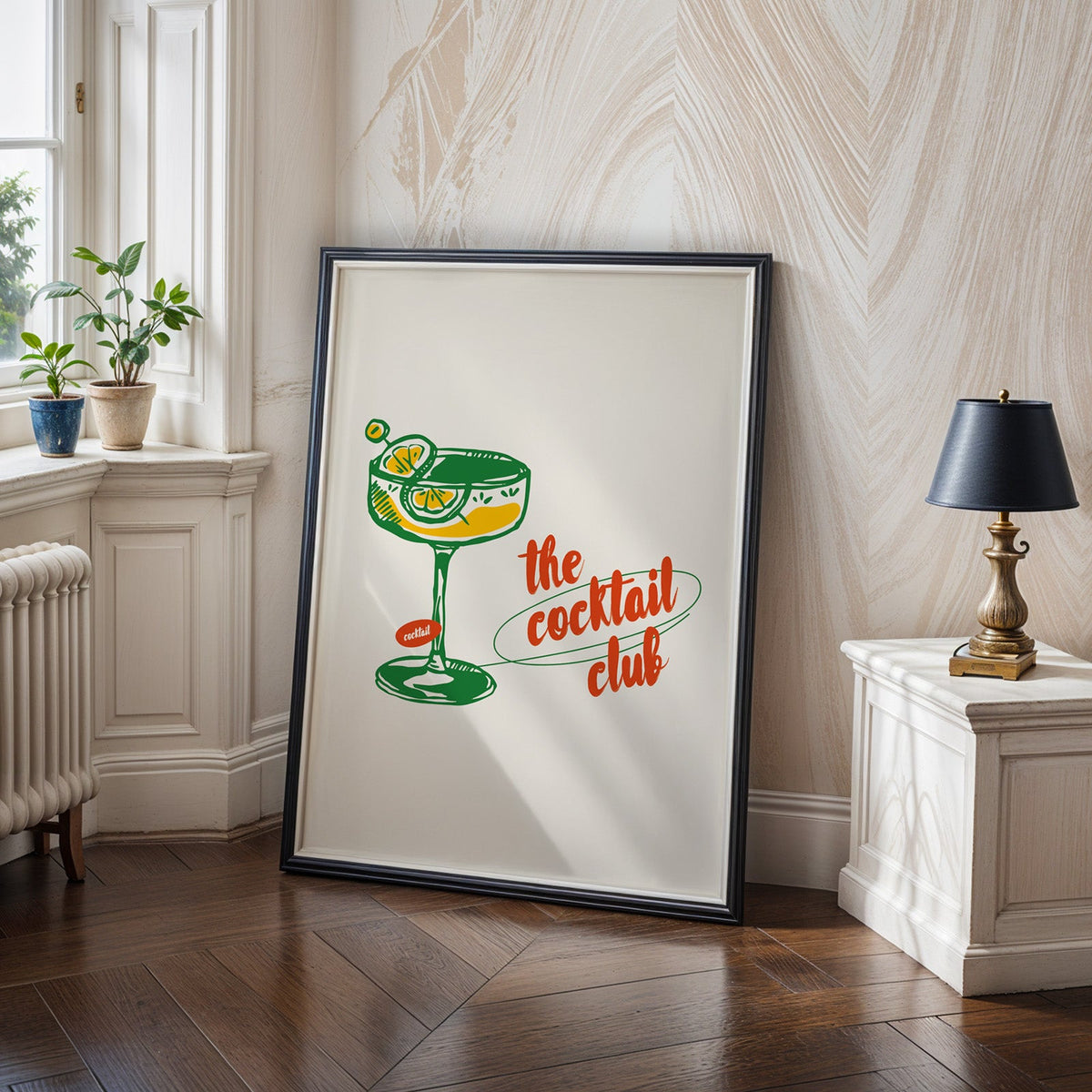 Cocktail poster in a black frame leaning on a herringbone wood floor in a panelled hallway