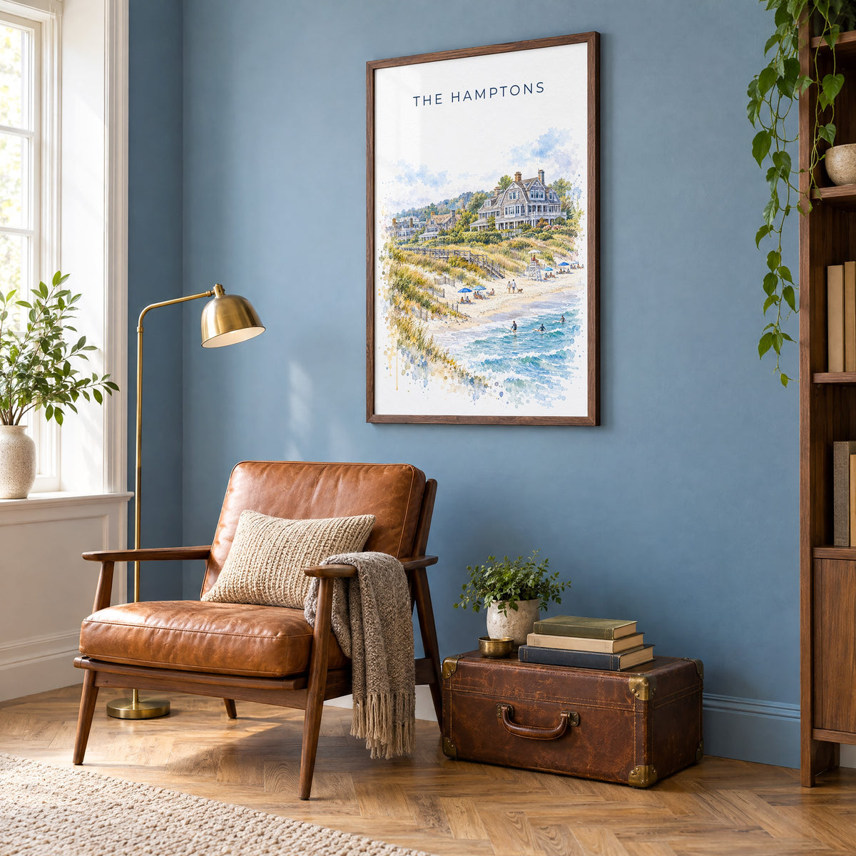 The Hamptons watercolor print in a walnut frame on a blue wall above a leather armchair in a reading nook