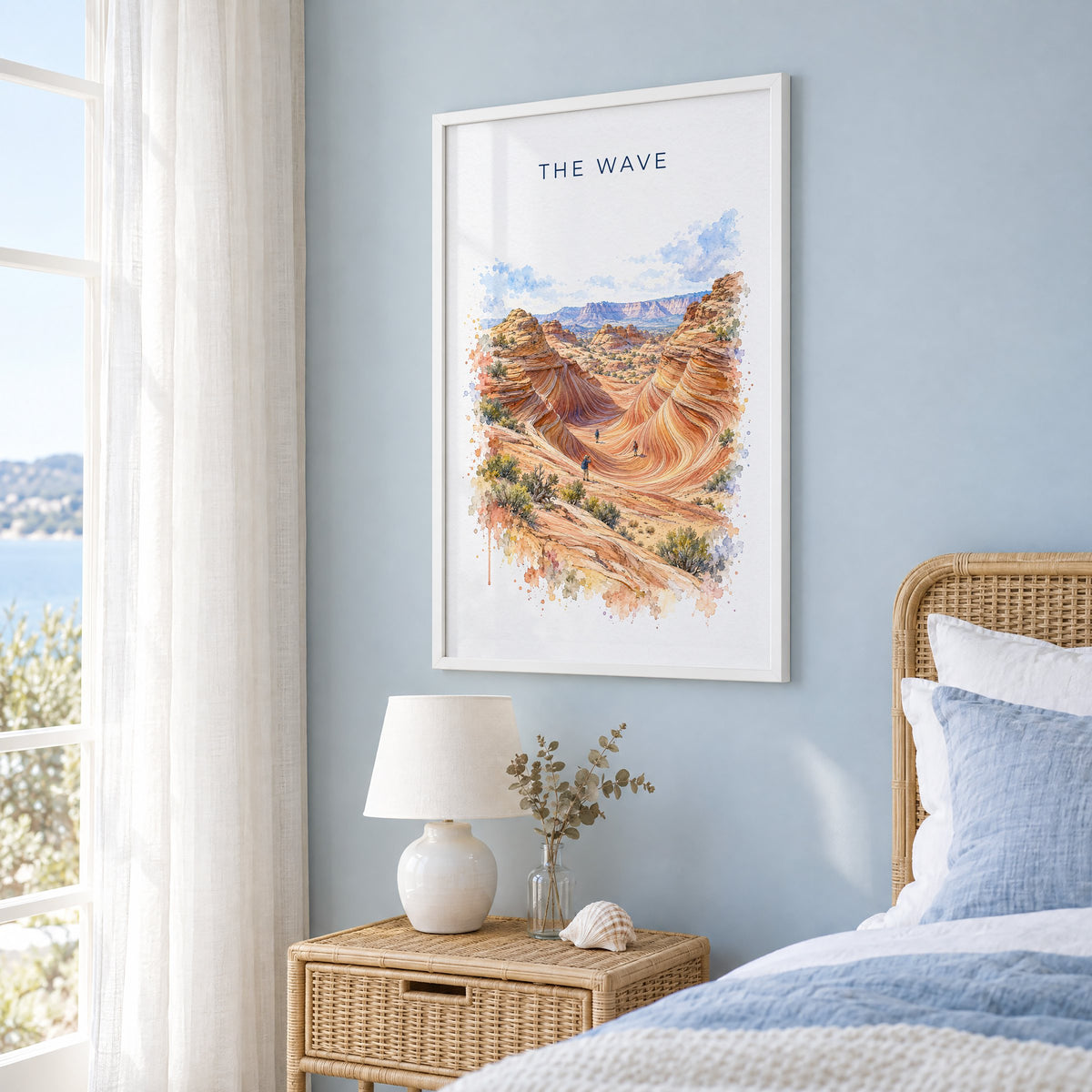 The Wave, Arizona watercolor print in a white frame on a pale blue wall beside a rattan bed in a coastal bedroom