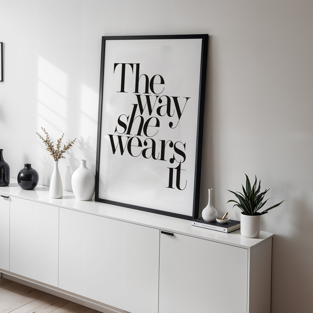 The way she wears it serif lettering print in a black frame on a white sideboard with black and white vases