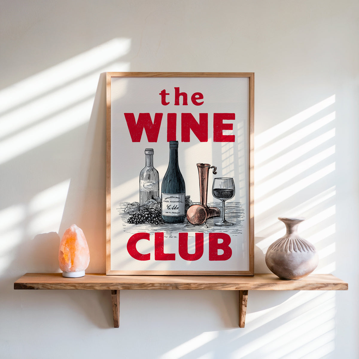 The Wine Club print in an oak frame on a live-edge shelf beside a salt lamp