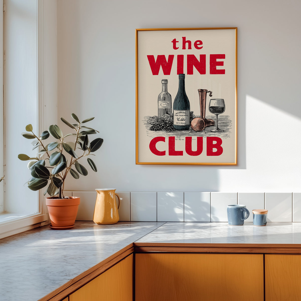 The Wine Club print shown in a gold frame above a marble counter in a tan kitchen