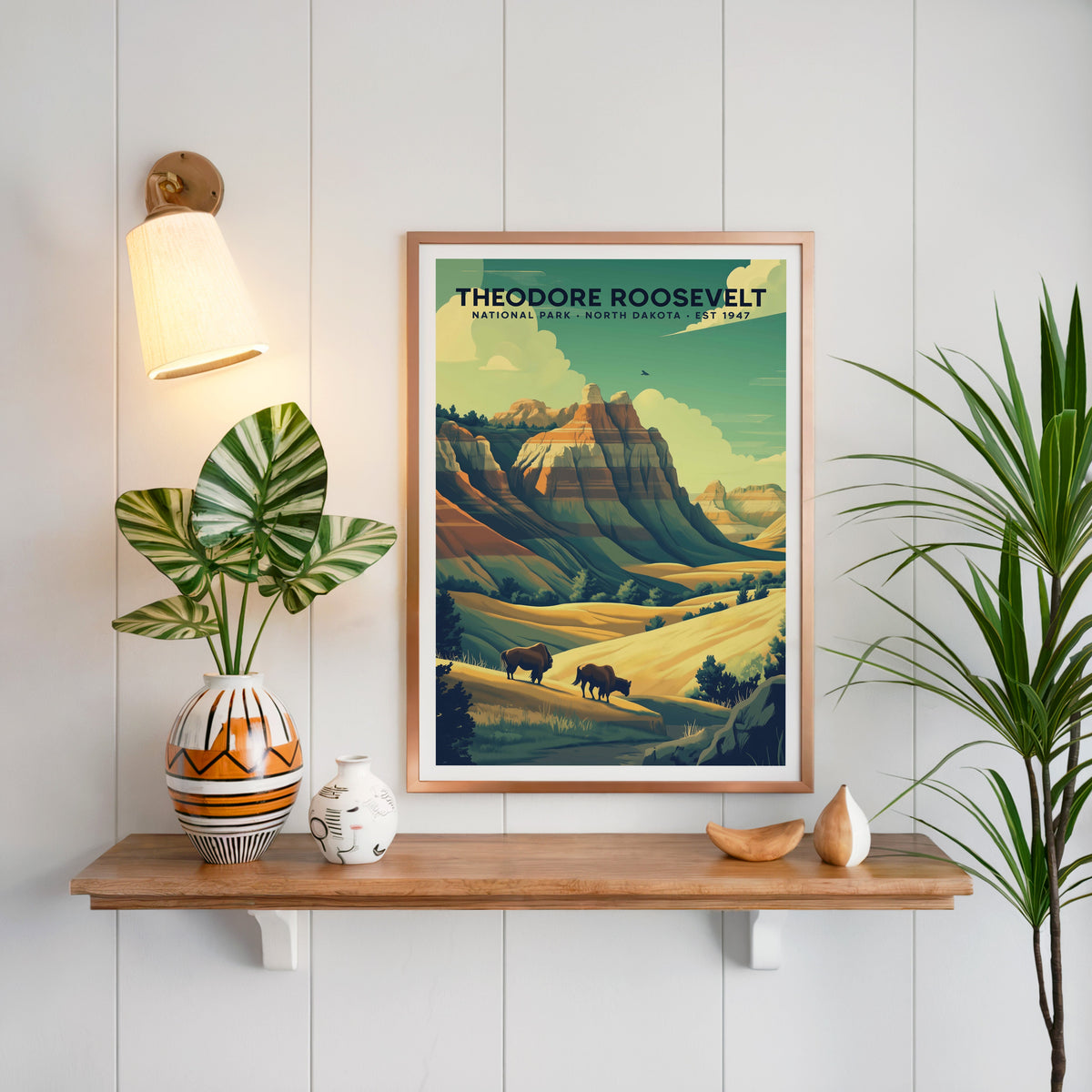 Theodore Roosevelt National Park print in a copper frame above an oak shelf on shiplap with a brass sconce
