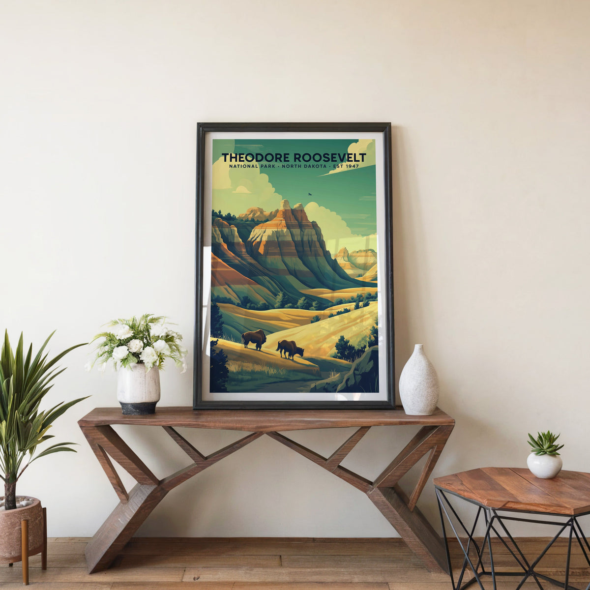 Theodore Roosevelt poster in a black frame on an entryway console table beside white flowers and a yucca