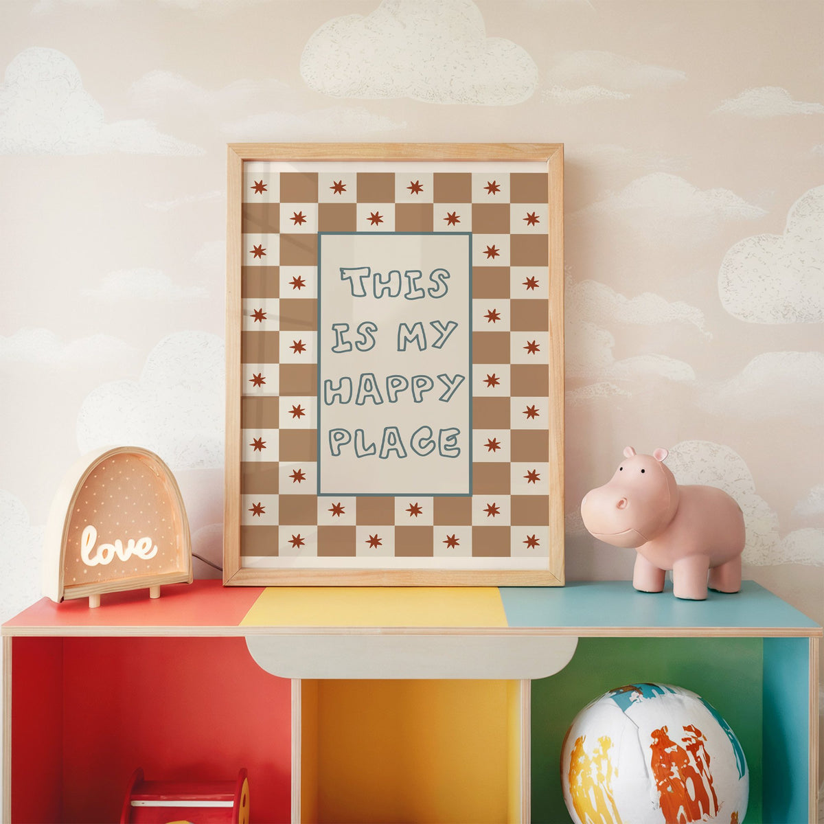 This is my happy place nursery print in an oak frame on a rainbow toy shelf against cloud wallpaper