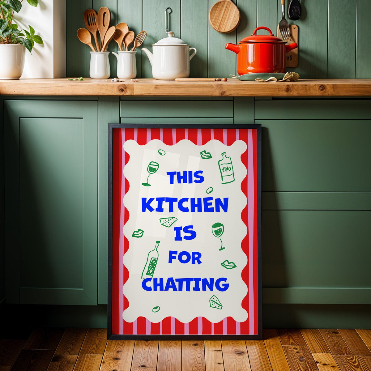 This kitchen is for chatting print in a black frame against sage green cabinets