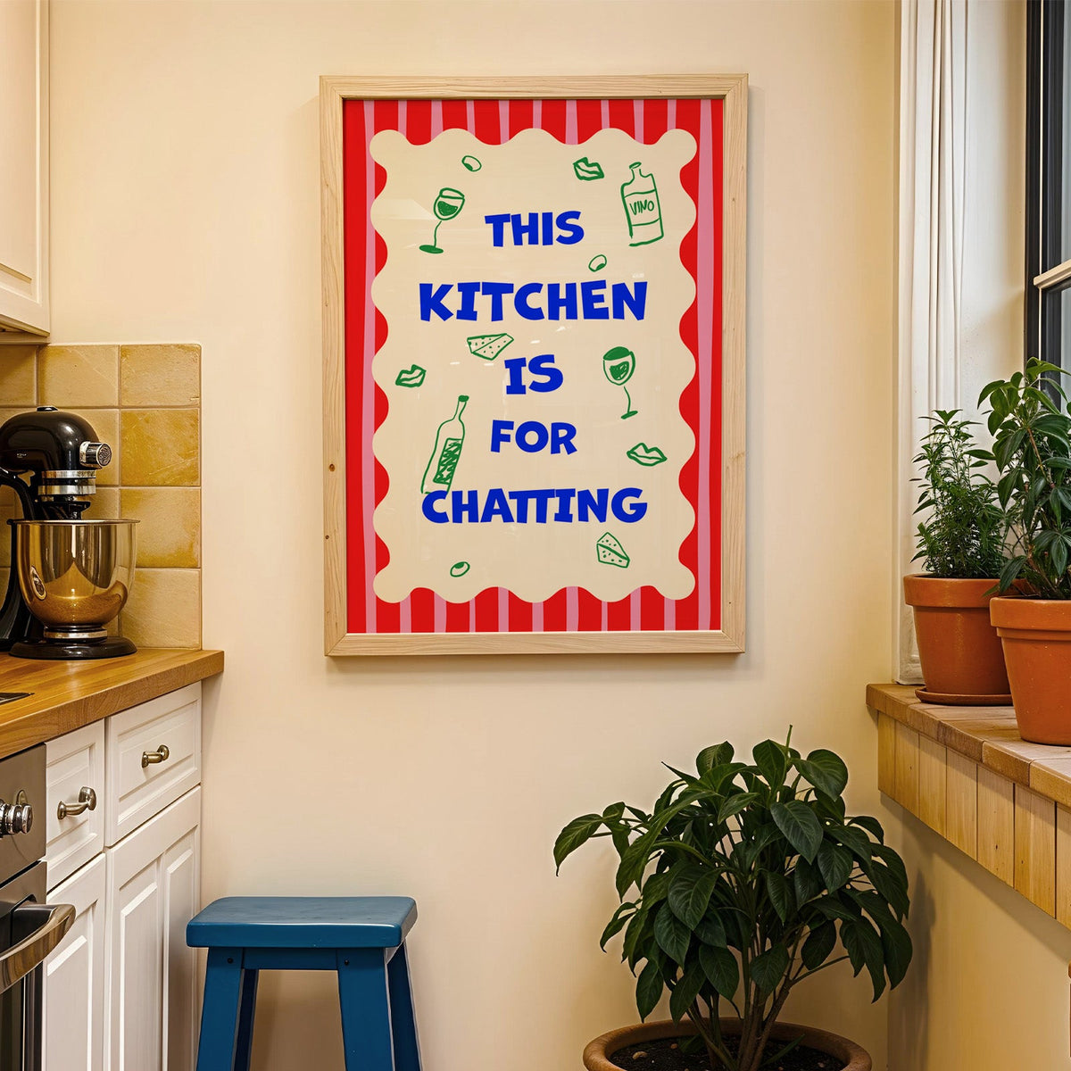 This kitchen is for chatting print in a wood frame on a yellow tiled kitchen wall