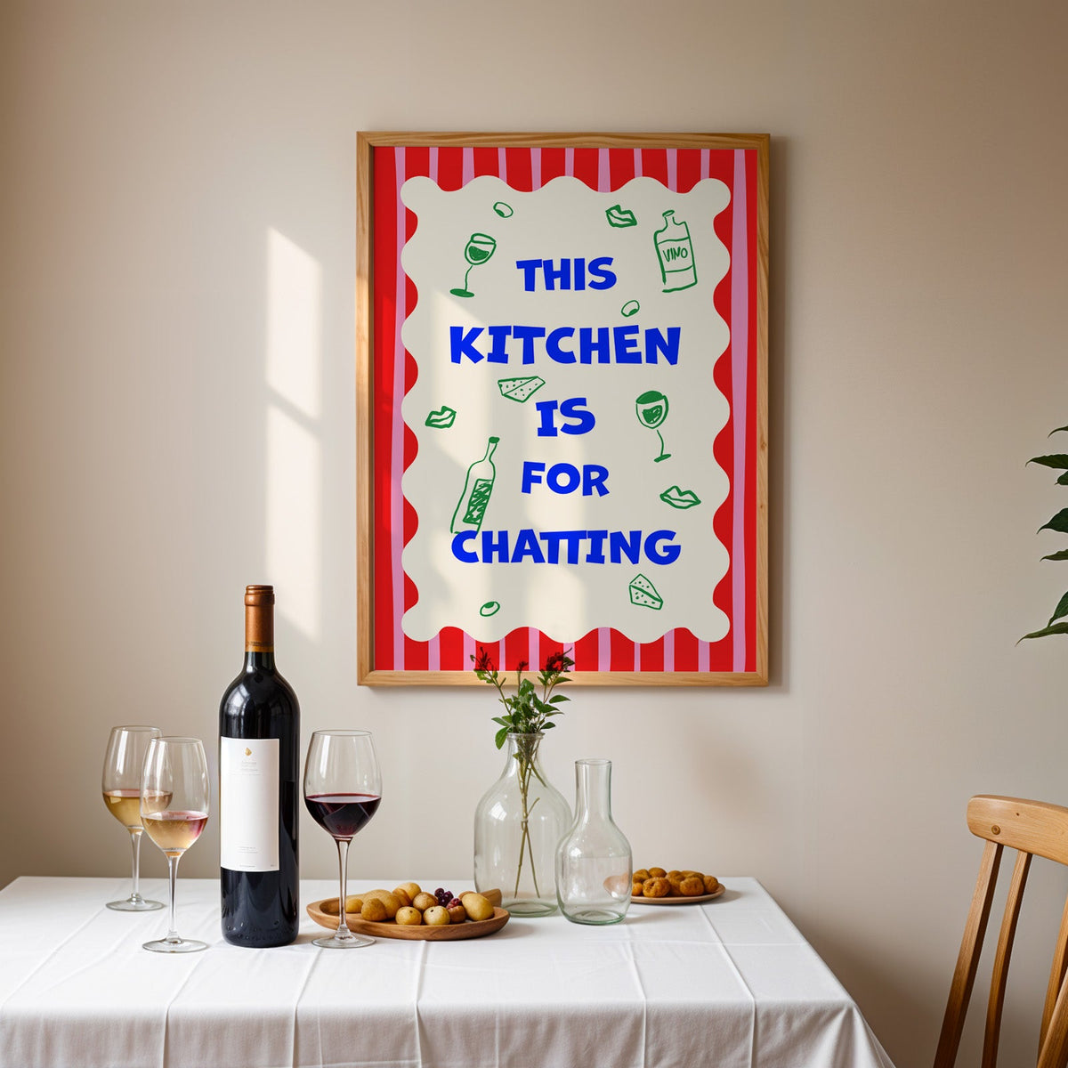 This kitchen is for chatting print in an oak frame above a table laid with red wine