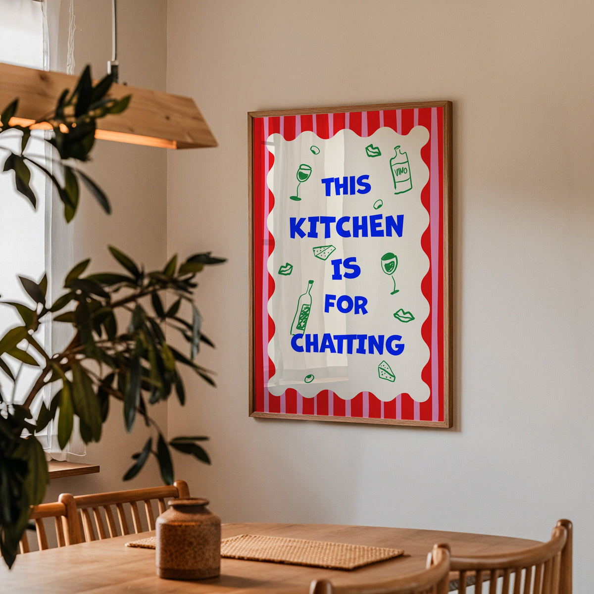 This kitchen is for chatting print in a walnut frame above a table beside an olive tree